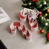 Red and white striped candy cane-shaped holder with cards with a christmas decor setting