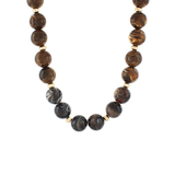 Necklace with round marbled brown and charcoal beads accented by small gold spacers, displayed on a white background