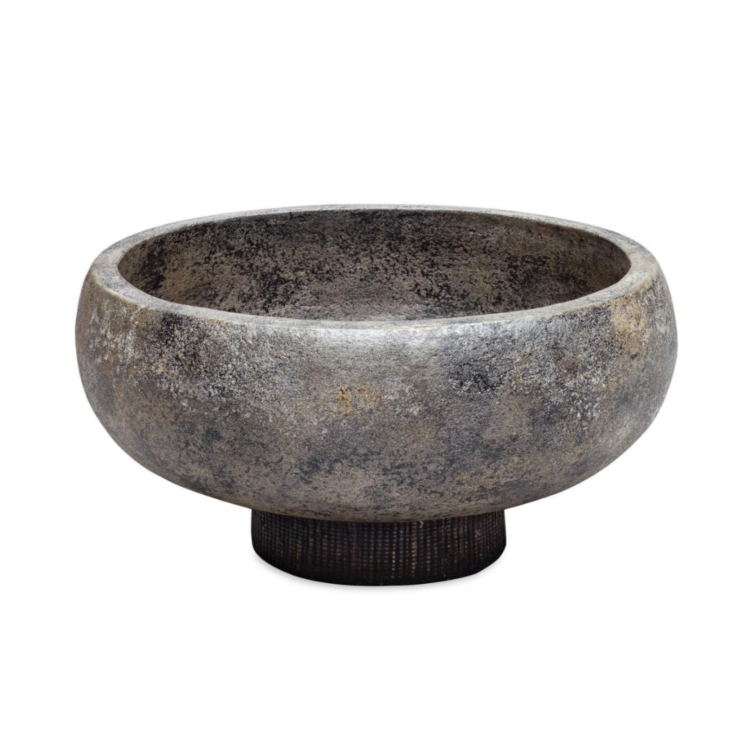 Round terracotta bowl with an aged black and gold finish, set on a woven water hyacinth base, styled as a decorative centerpiece on a white background