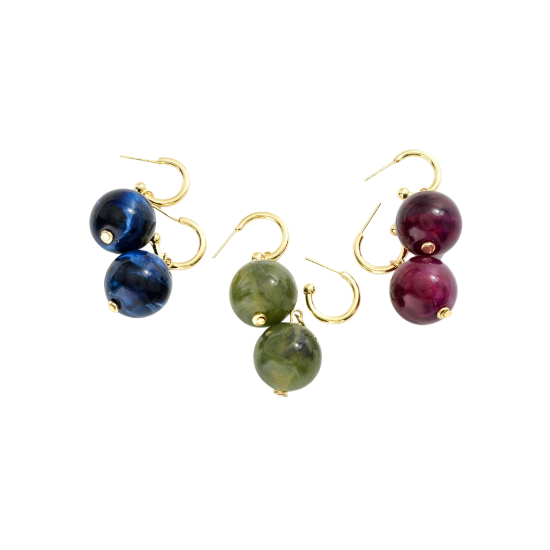 Set of three pairs of earrings with multicolored beads on a white background