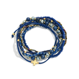 Stack of blue beaded bracelets with gold accents on a white background