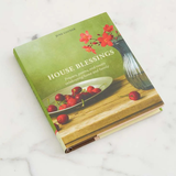 Book titled 'House Blessings' with a green cover featuring cherries and flowers on a white marble surface.