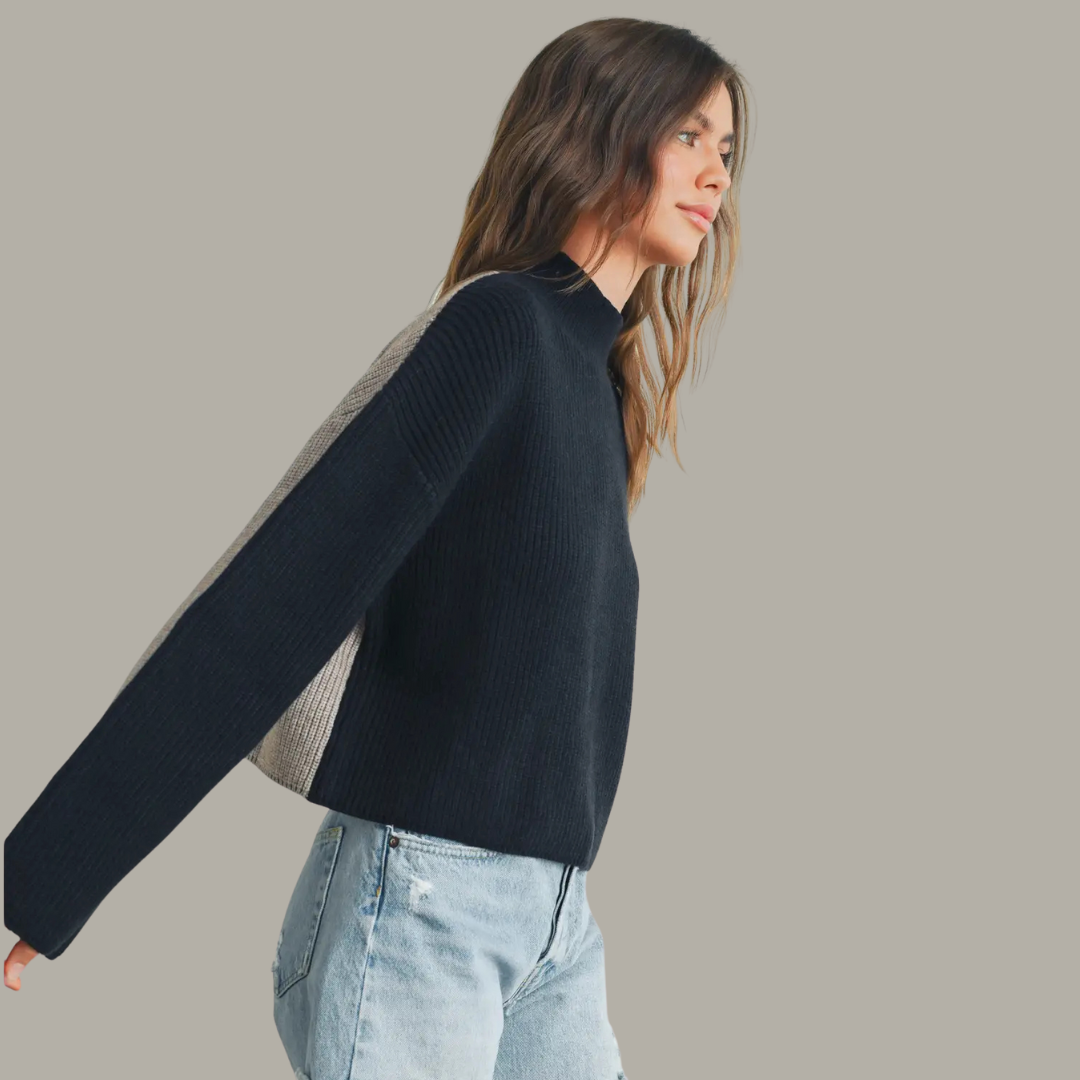 Woman wearing a dark blue sweater and light blue jeans against a plain background