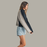 Woman wearing a two-tone cardigan with a plain background