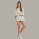 Woman wearing a patterned sweater and shorts on a plain background