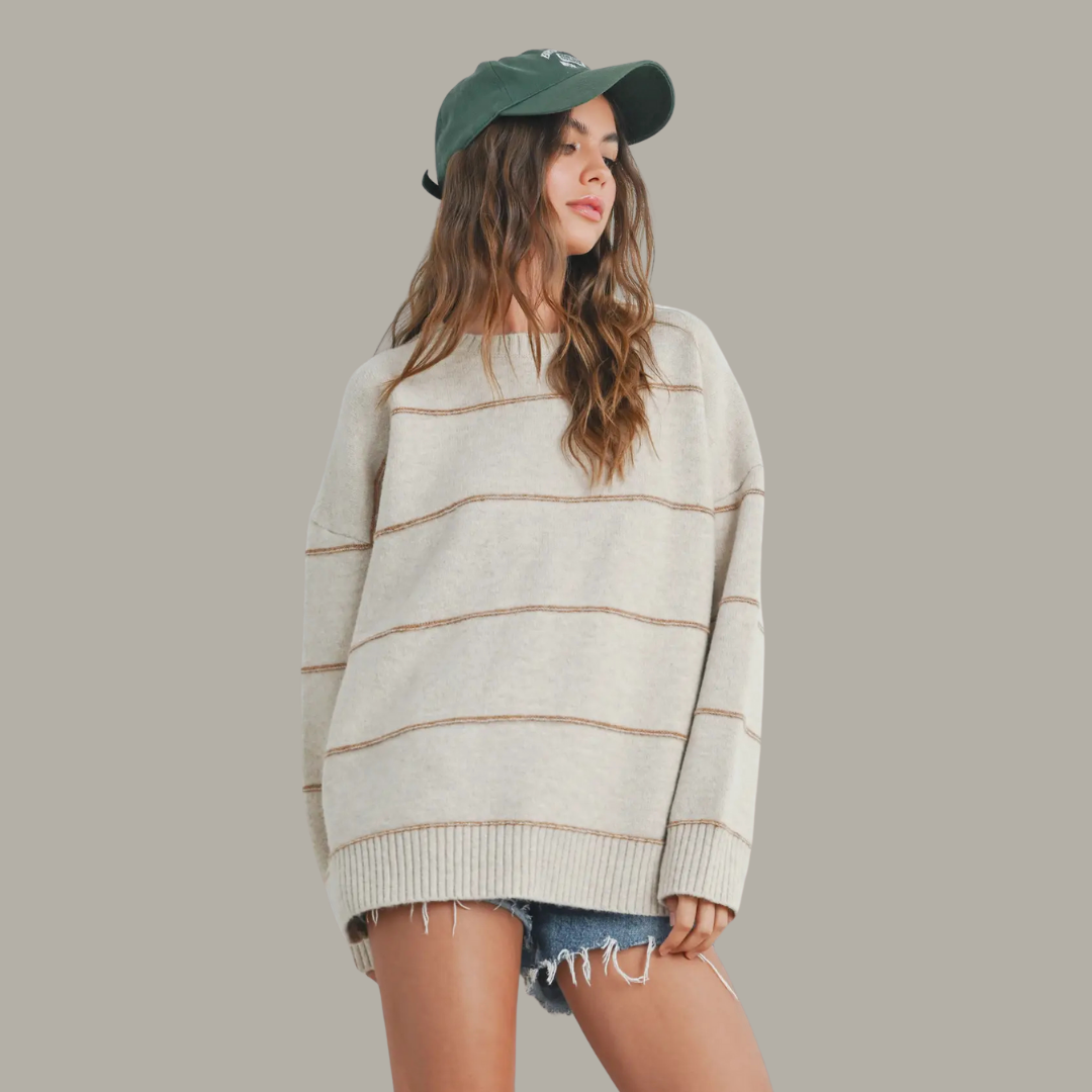 Woman wearing a striped sweater and green cap on a gray background