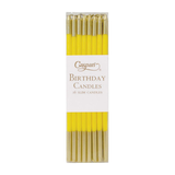 Pack of yellow birthday candles with gold tips in a Caspari branded box on a white background