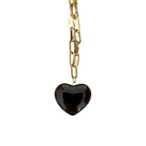 Gold chain necklace with a heart-shaped black pendant on a white background
