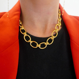 Gold chain necklace worn by a person with a red jacket and black shirt.