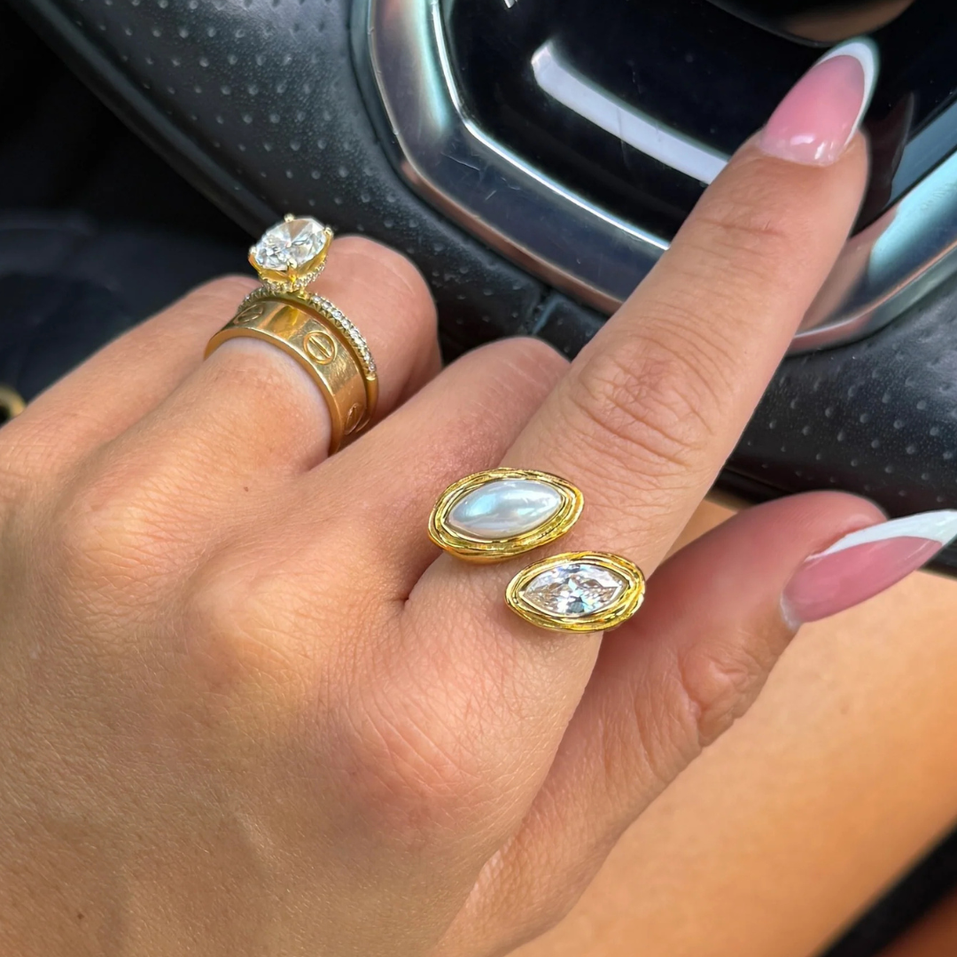 Gold earrings and ring on a hand with a blurred car interior background