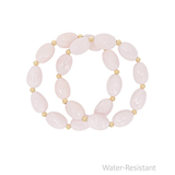 Pink beaded bracelet with gold accents on a white background