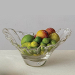 Clear glass bowl with fruits on a light gray background