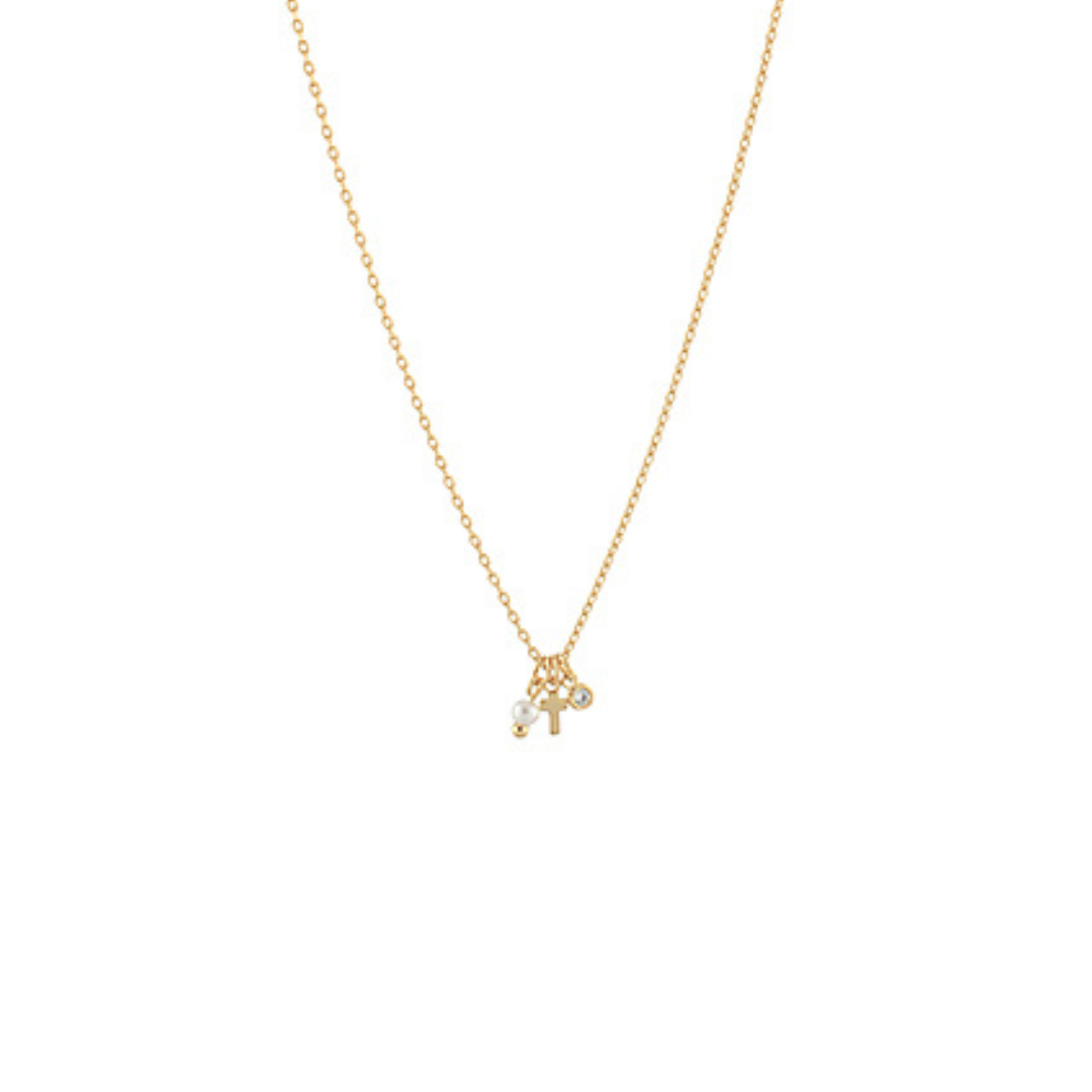 Delicate gold charm necklace with small charms including a mini cross, photographed on a white background.