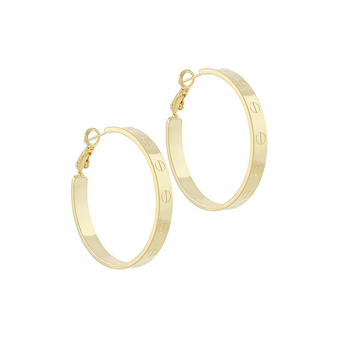 Gold hoop earrings with engraved nail head detailing, photographed on a white background.