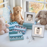 Baby-themed decor with teddy bears, photo frames, and alphabet blocks on a light surface.