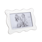 White decorative photo frame with a black and white photo of three children inside.