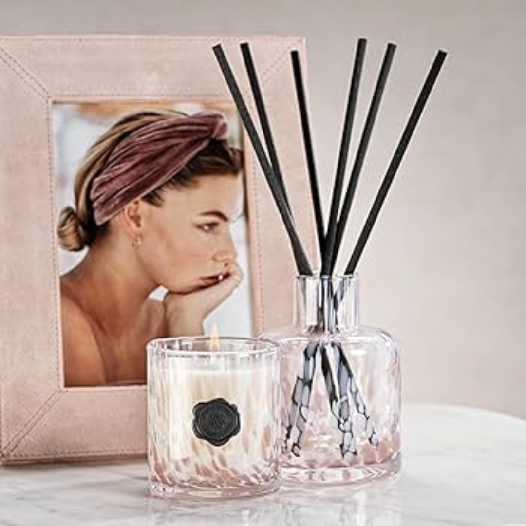Candle and diffuser with a blurred photo of a woman in the background