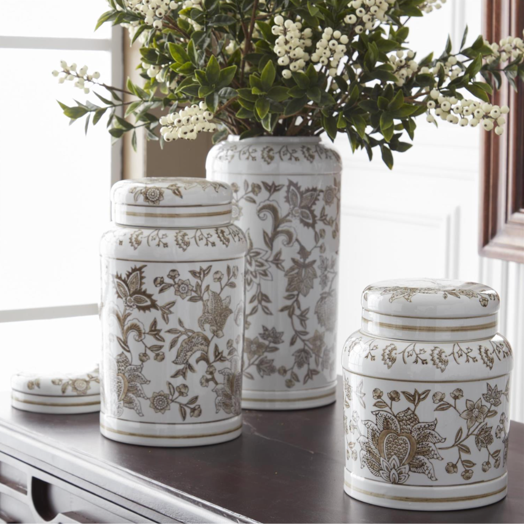 Set of three decorative ceramic jars with floral patterns on a table.