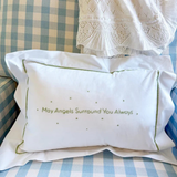 White pillow with 'May Angels Surround You Always' text on a checkered fabric background