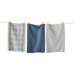 Three textured blue dishtowels hanging on a clothesline against a white background
