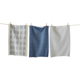 Three textured blue dishtowels hanging on a clothesline against a white background