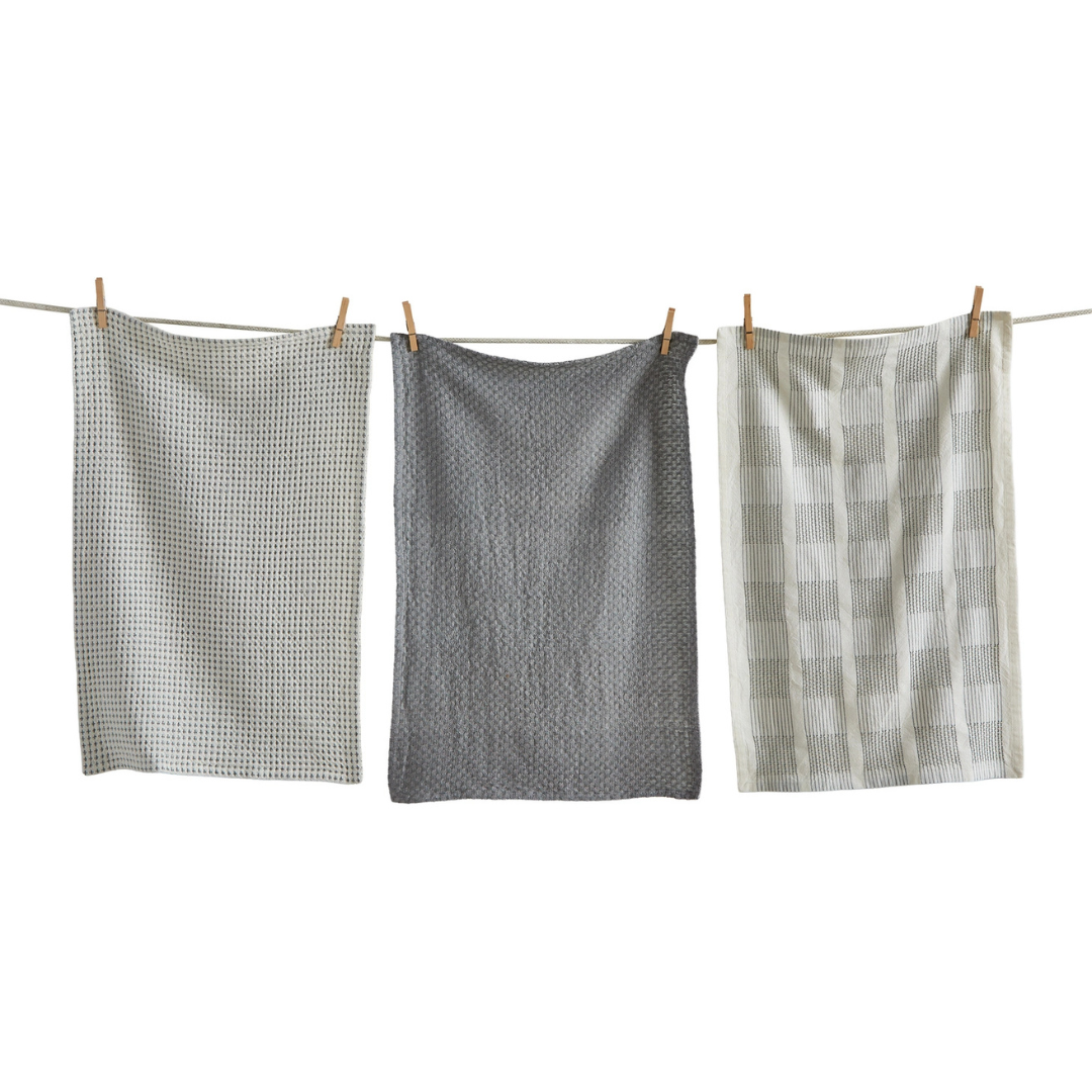 Three textured gray dishtowels hanging on a clothesline against a white background