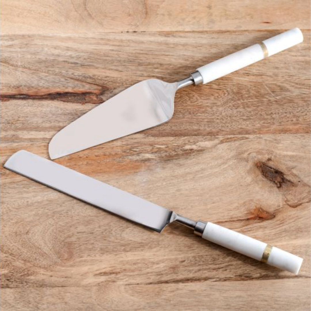 Two cake knives with white handles on a wooden surface