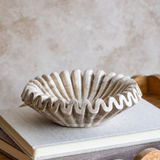 Decorative beige marble bowl on a book with a neutral background