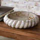 Decorative stone bowl on a wooden surface with a blurred brick wall background