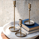 Three brass candle holders on a textured surface with a neutral background