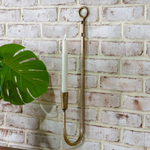 Decorative wall hook with a candle against a brick wall