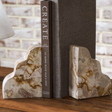 Marble bookends holding a book titled 'Create' on a wooden surface.