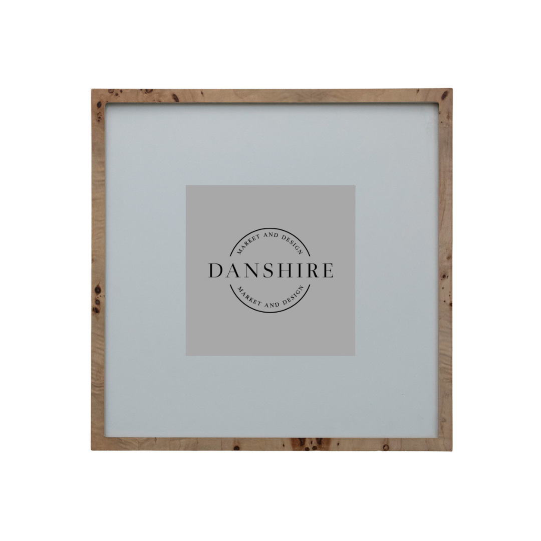 A square picture frame with a natural light brown wood border and a light gray mat, featuring a central gray placeholder card with the brand name 'DANSHIRE' printed in black.