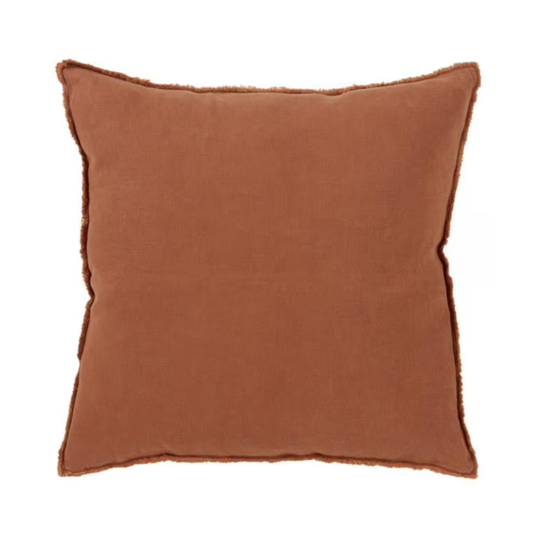 A square throw pillow in a warm rust brown color with a frayed, raw-edge trim, shown against a plain white background.