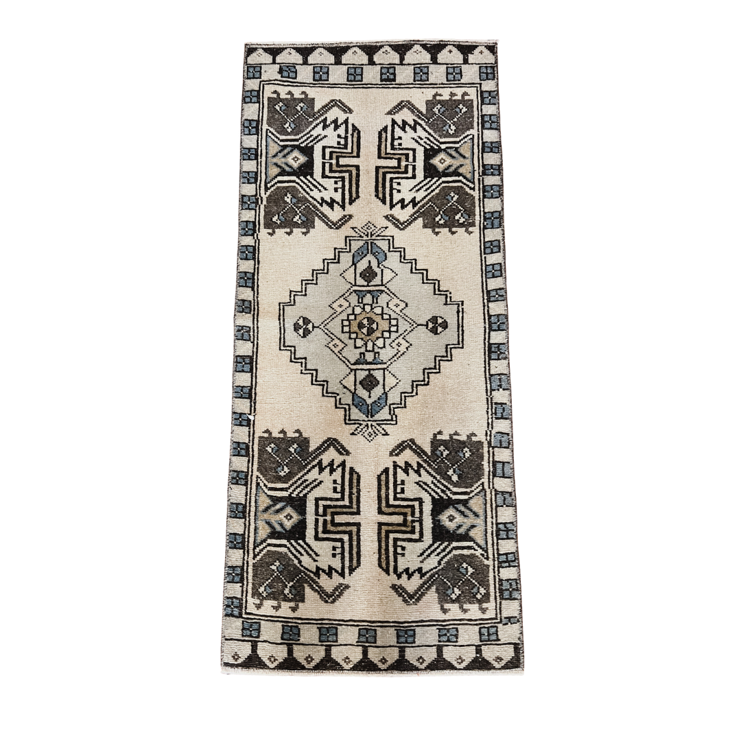 Ivory accent rug with tribal geometric medallion pattern in charcoal, taupe, and muted blue, 19 x 44 inches, vintage-inspired runner-style rug.