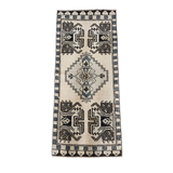 Ivory accent rug with tribal geometric medallion pattern in charcoal, taupe, and muted blue, 19 x 44 inches, vintage-inspired runner-style rug.