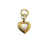 Gold heart charm with a white center stone, photographed on a neutral background.