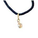 Deep navy faceted disc bead necklace with gold clasp and extender, shown styled with a gold crescent moon charm accented with a pearl on a white background.