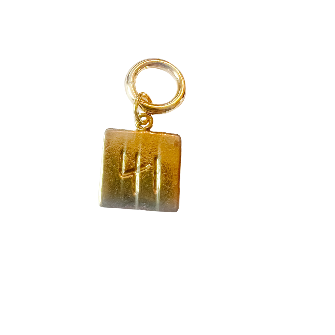 Gold charm with a square pendant on a white background