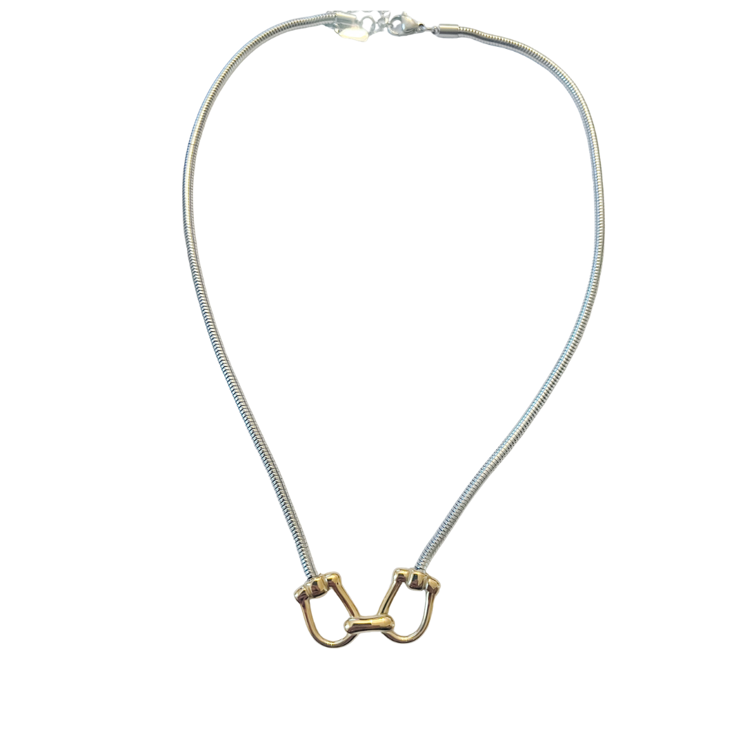 Silver snake chain necklace featuring a gold equestrian horse-bit centerpiece with mixed metal detailing on a white background.