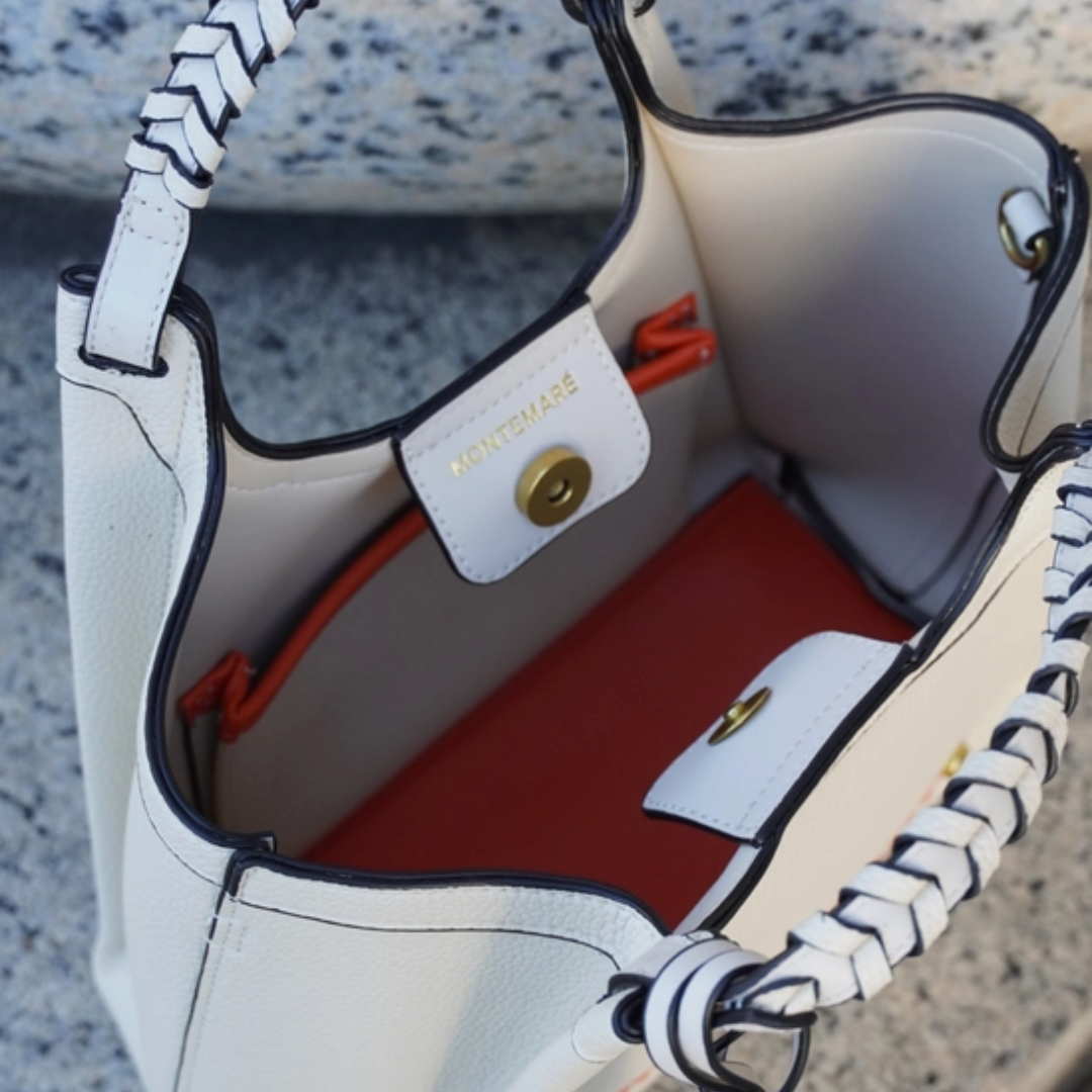 White handbag with black and white striped handles, red interior, and visible brand name.