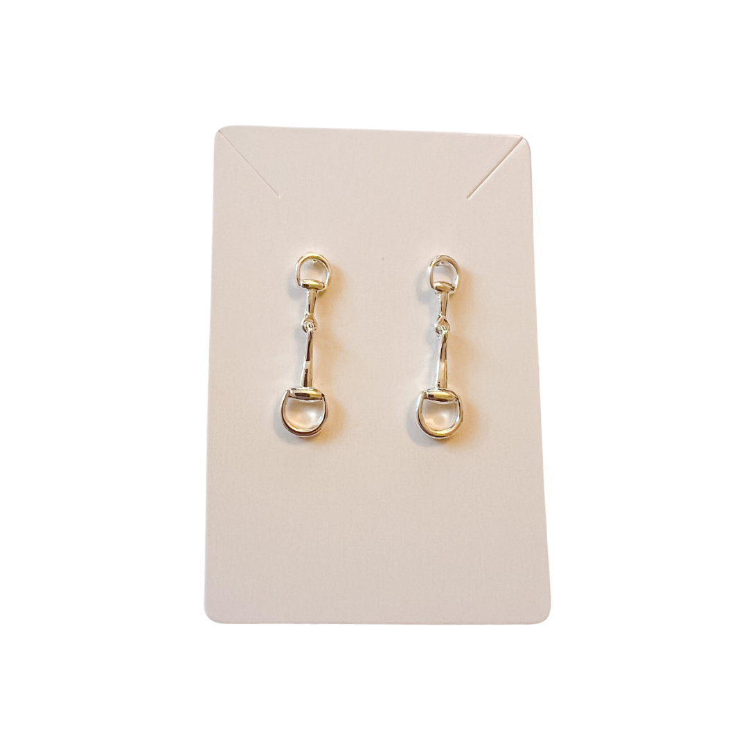 Gold earrings on a beige card against a white background