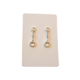 Gold earrings on a beige card against a white background
