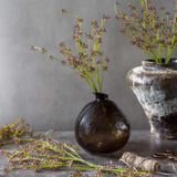 Two vases with dried plants on a gray surface against a neutral background