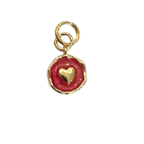 Small red coin charm with raised gold heart detail and gold frame on a white background.