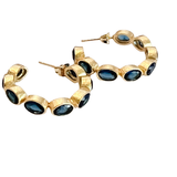 Gold hoop earrings with blue gemstones on a white background
