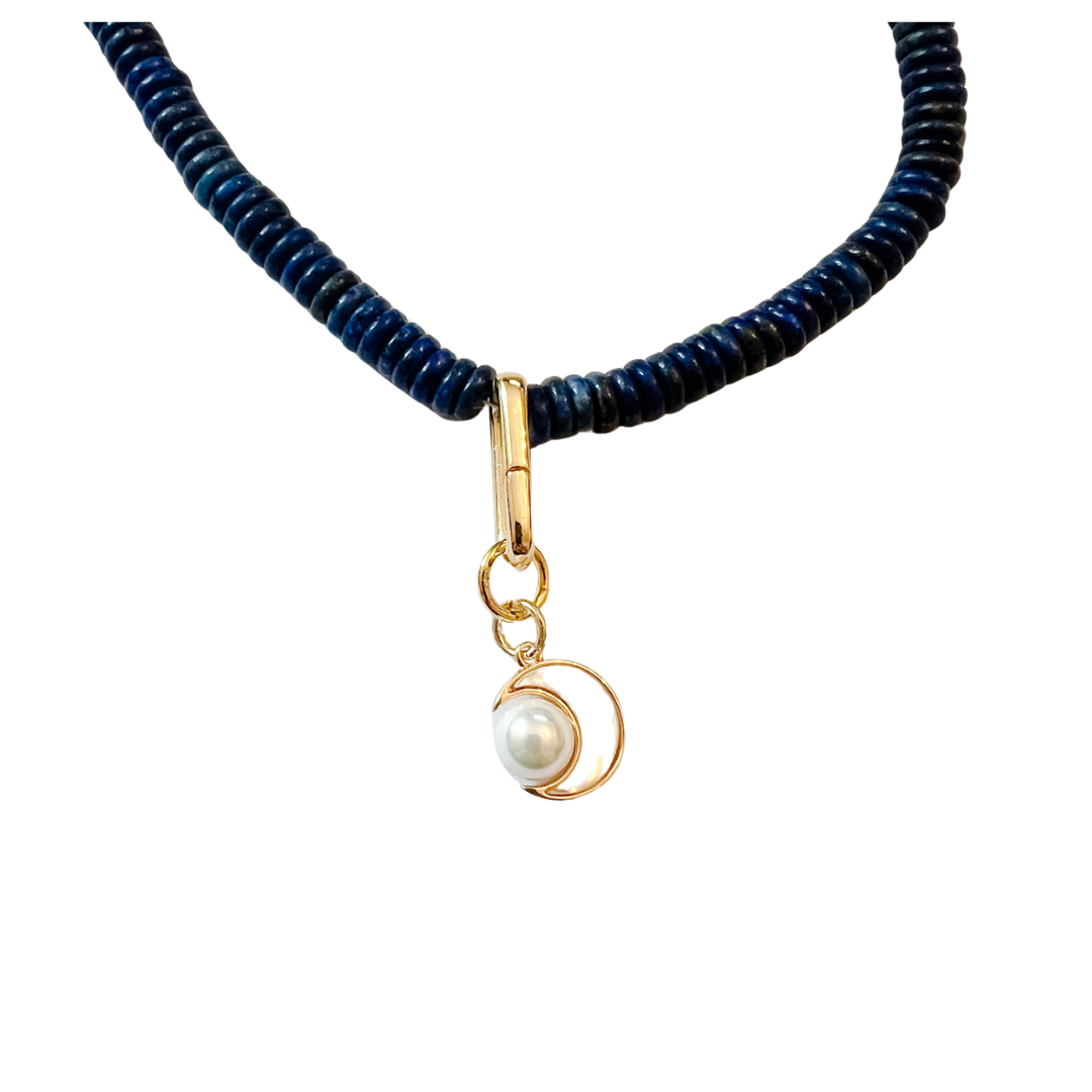 Pearl crescent charm with gold setting on a beaded necklace.