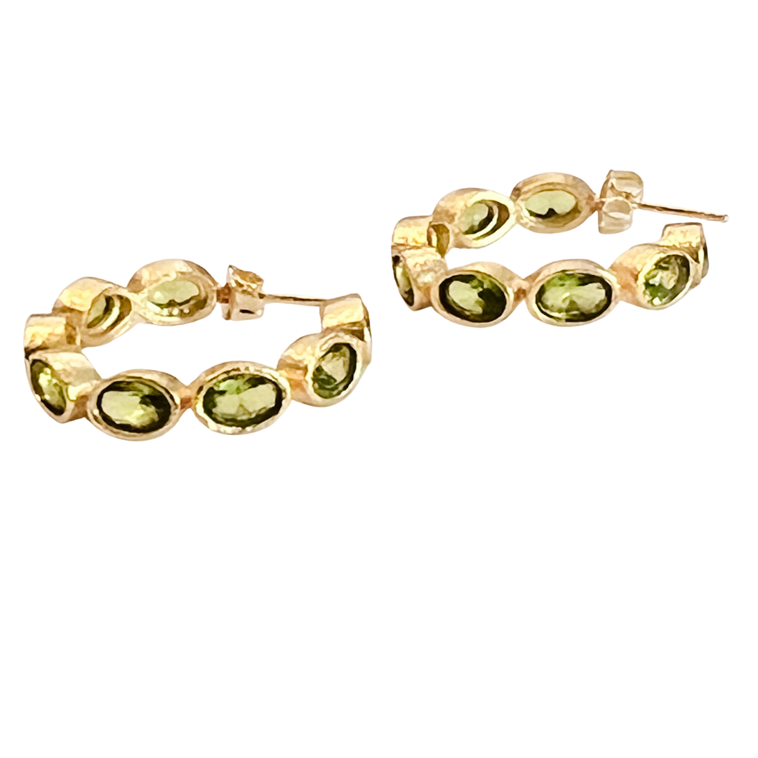 Gold hoop earrings with green gemstones on a white background