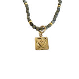 Faceted stone bead necklace with gold accents featuring a removable gold square charm with heart detail.