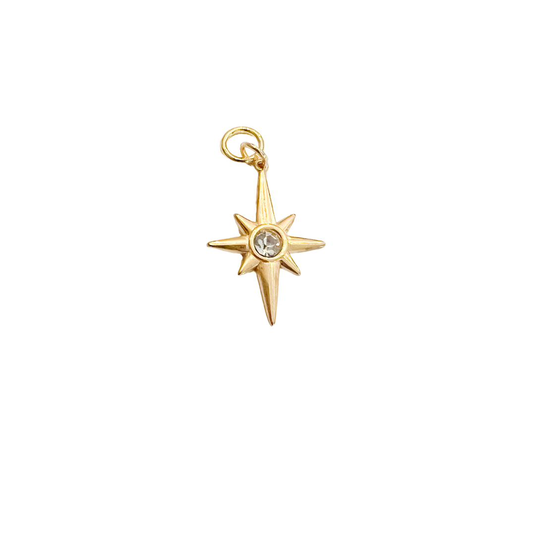 Gold North Star charm with crystal center and small attachment loop on a white background.